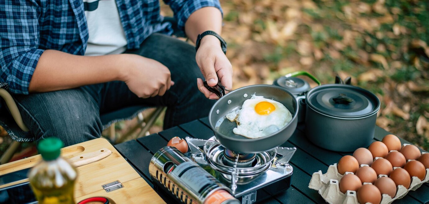 Front Page -UK Outdoor Equipment Sales 2024 portrait asian traveler man glasses frying tasty fried egg hot pan campsite outdoor cooking traveling camping lifestyle concept 1150 61557